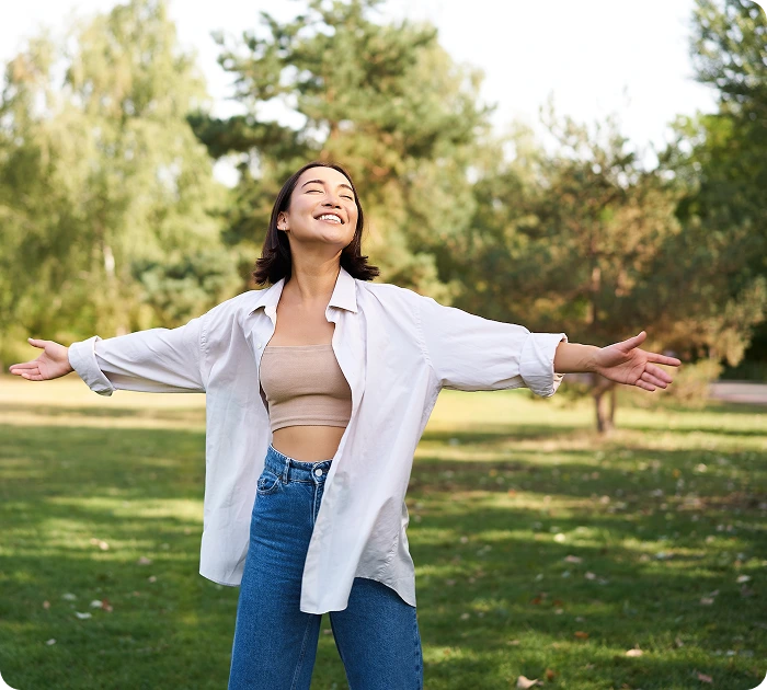 woman with her arms wide open in a field feeling breathing free