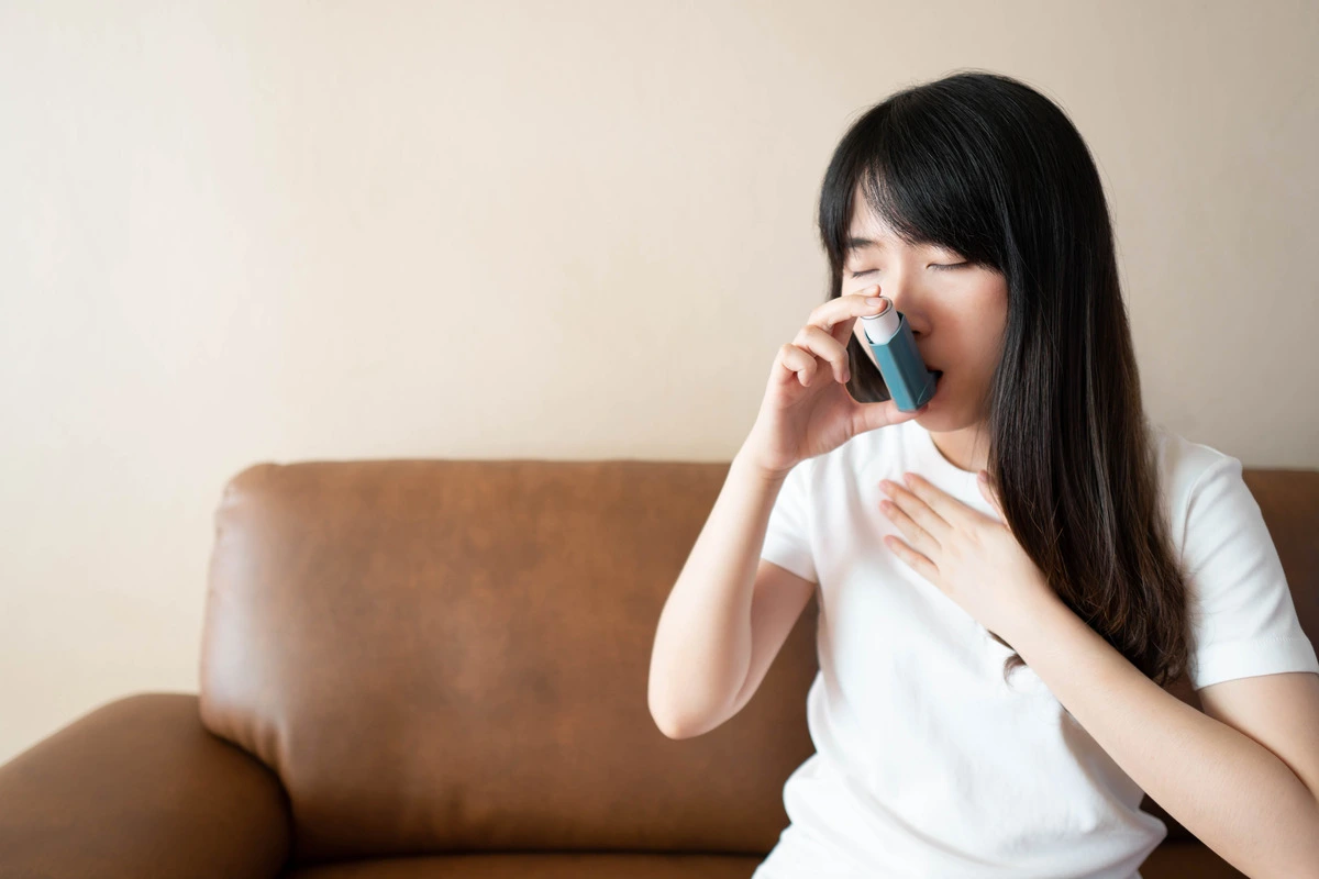 Woman experiencing an asthma attack while using an inhaler for relief as asthma treatment