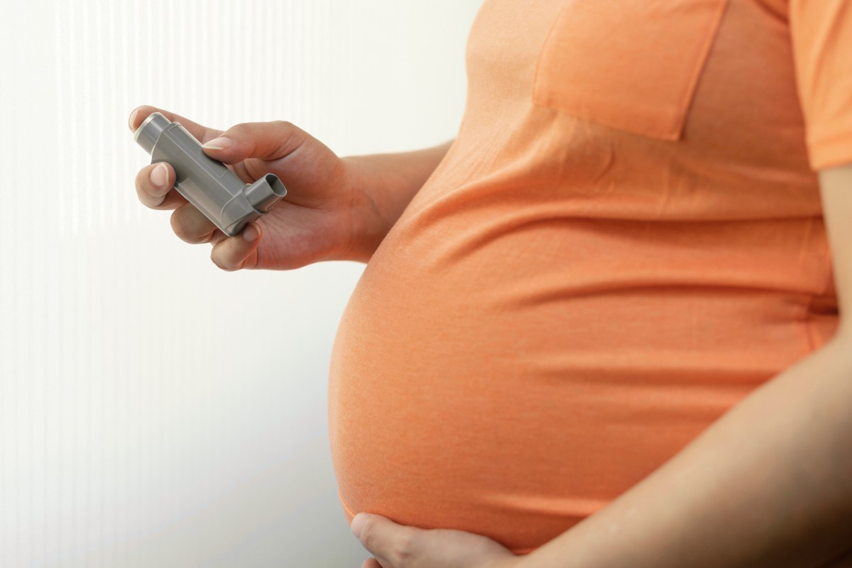 a pregnant woman holding an inhaler near her belly